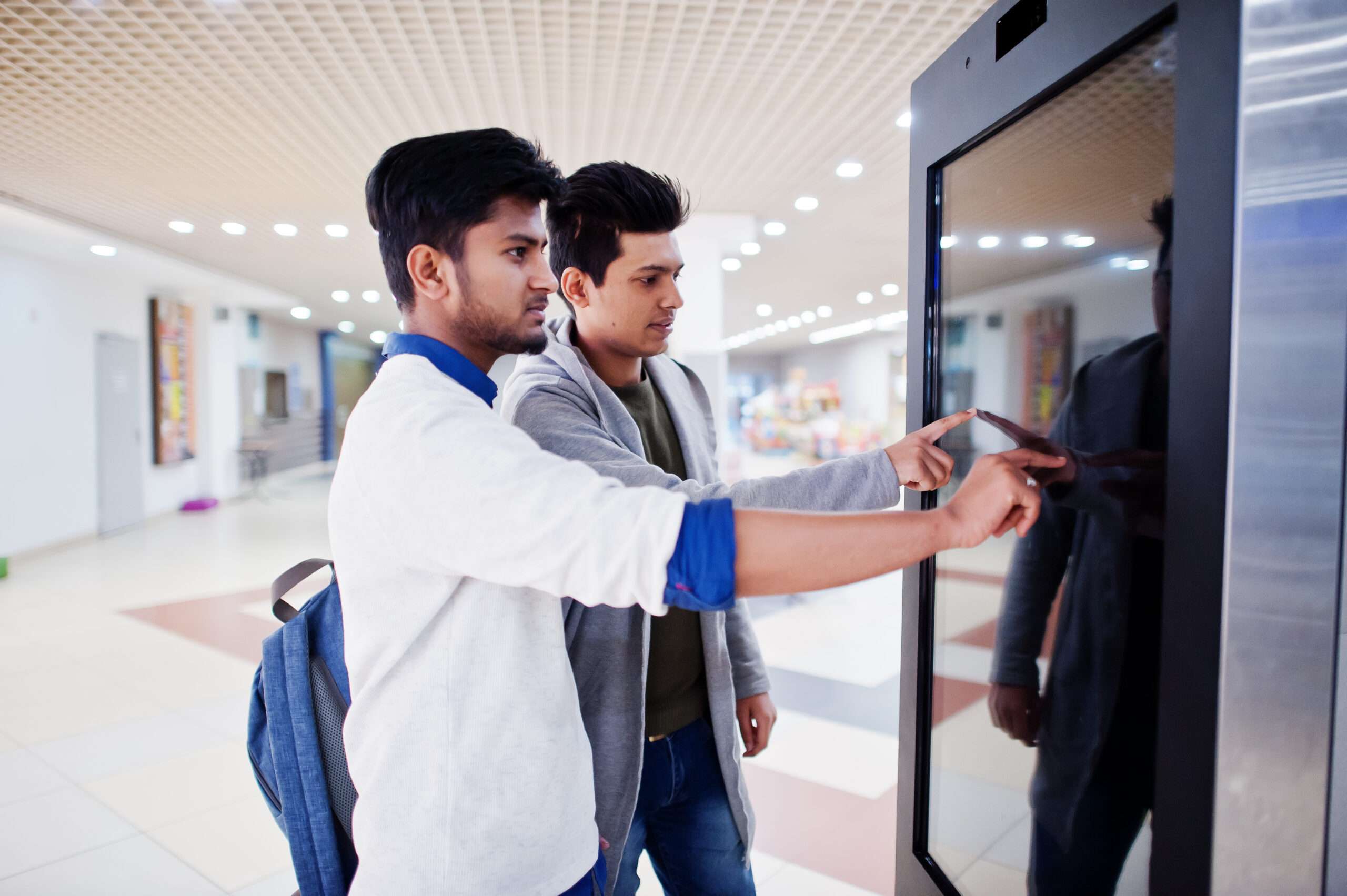 two asian guys touching screen electronic information desk mall scaled